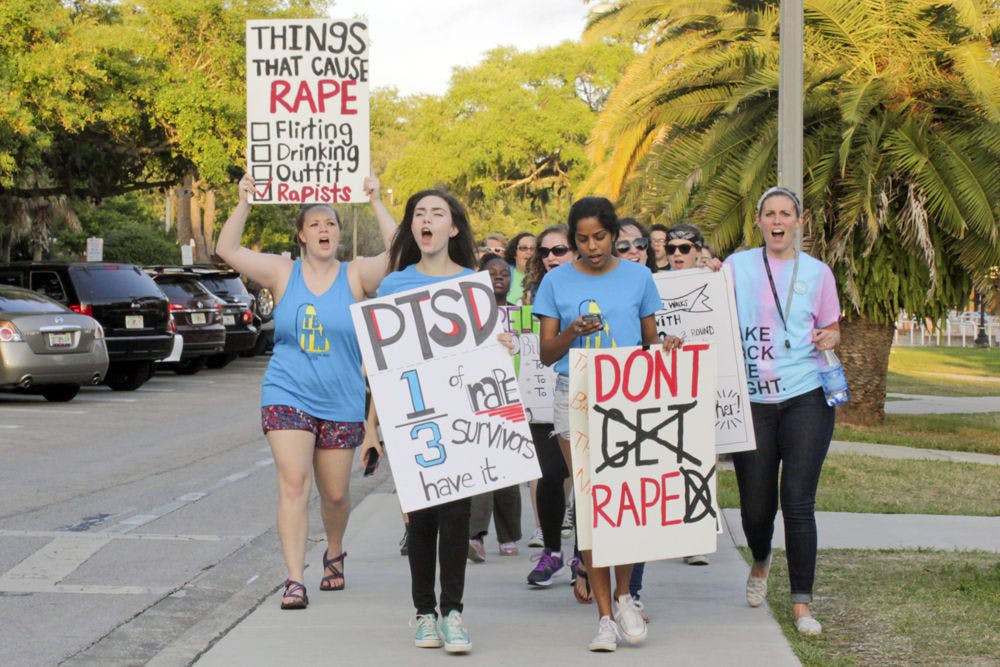 <p>Madeleine Hill, Alissa Kotranza and Kriti Vedhanayagan, all UF students, and UFPD victim advocate Anne Carper march west on Inner Road in the Take Back the Night march to end sexual violence. “Yes means yes. No means no. Whatever we wear, wherever we go,” they chanted.</p>