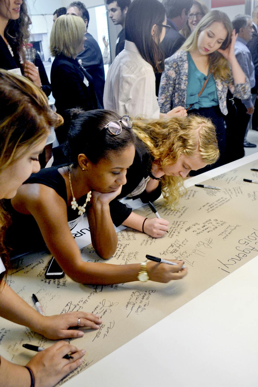 <p>Members of the inaugural Agency team write messages and sign their names on a strip of paper in the new facility on Tuesday afternoon. The signatures will be placed in a time capsule.</p>