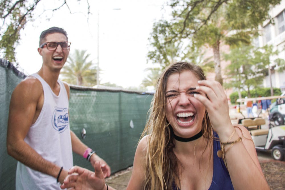 From left: UF students Richard Minichiello and Sarah Galante laugh while facing the rain before the UF Homecoming football game on Saturday afternoon. They “couldn’t believe they got soaked,” said Galante.