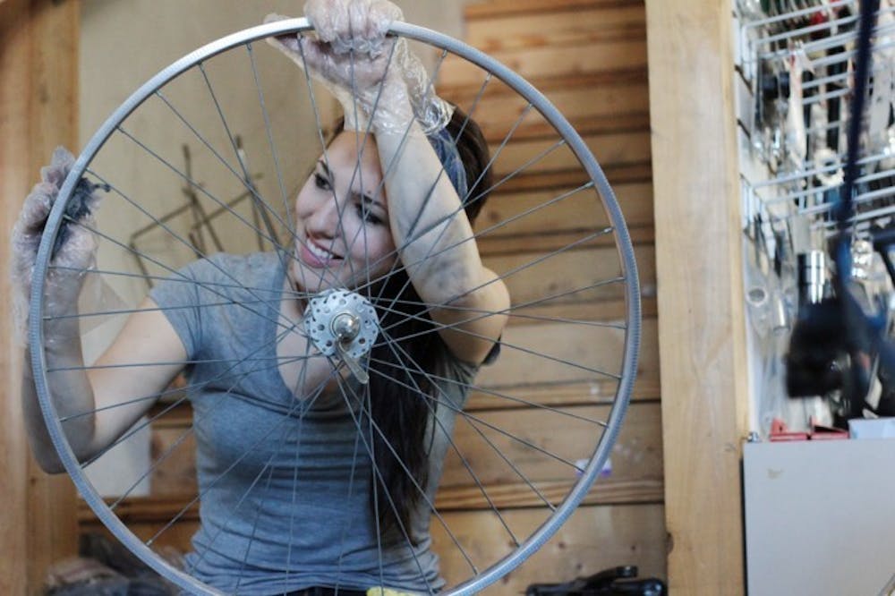 <p>Kathleen Bly, 25, cleans the rust off an Italian wheel with steel wool at The 8th Ave Bike and Coffee House, which is participating in the UF Office of Sustainability's Bicycle Benefits program.</p>