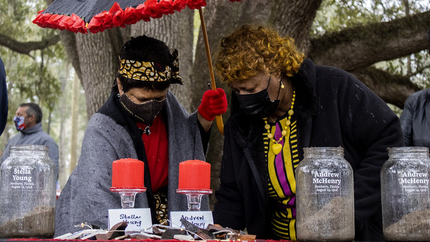 Gail K. Watson (left) and Brenda Whitfield (right) scoop dirt into glass jars at the soil ceremony for the Newberry Six on Friday, Feb. 5, 2021. Whitfield spoke during the ceremony before the crowd began adding earth to the containers.