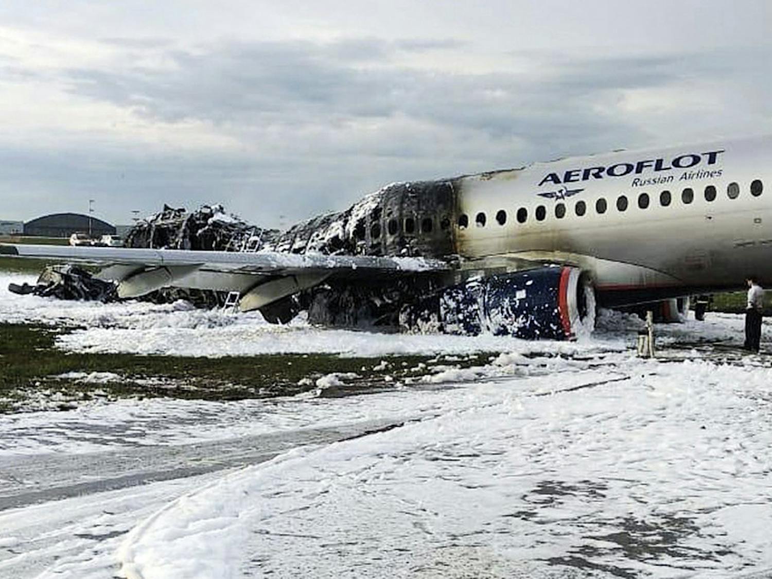 The Sukhoi SSJ100 aircraft of Aeroflot airlines is covered in fire retardant foam after an emergency landing in Sheremetyevo airport in Moscow, Russia, Sunday, May 5, 2019. Scores of people died when the Aeroflot airliner burst into flames while making the emergency landing at the airport Sunday evening, officials said.