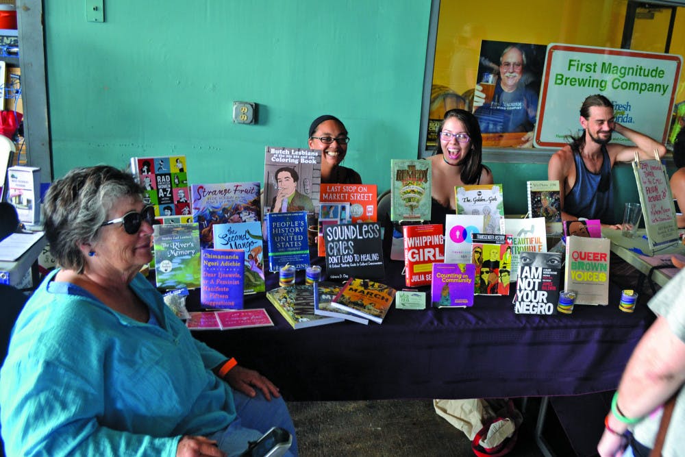 Erica Merrell and her associate from Wild Iris Books, Florida’s first feminist bookstore, laugh with patrons at the Pride Extravaganza event Sunday.