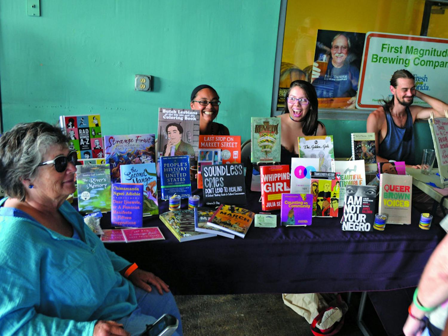 Erica Merrell and her associate from Wild Iris Books, Florida’s first feminist bookstore, laugh with patrons at the Pride Extravaganza event Sunday.