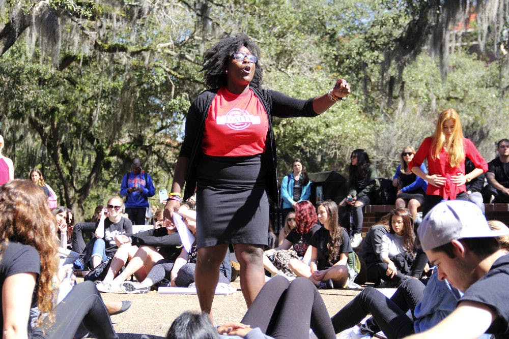 <p>Bertrhude Albert leads the Global Awareness Flash Mob at Turlington Plaza on Tuesday. Participants froze in place for five minutes while other students shouted statistics on current issues in the world. Albert teaches a class of 200 students that focuses on heightening oral communication skills.</p>