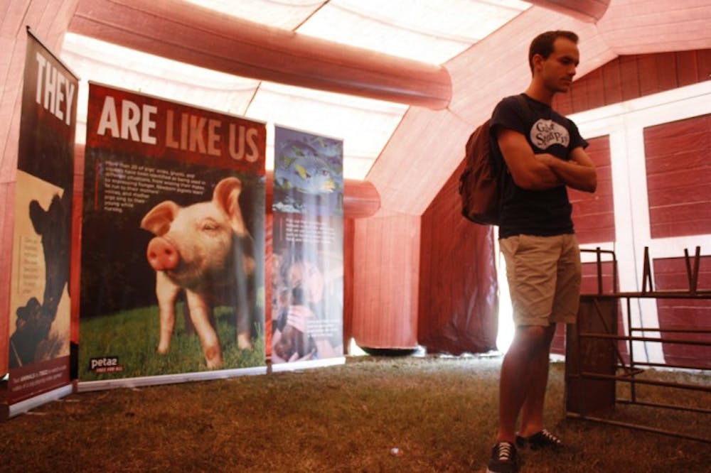 <p>Chemical engineering senior Jhon Cores, 22, reads a banner about the abuse of chickens in peta2's inflatable factory farm on Wednesday afternoon. The farm will be on the Plaza of the Americas through Friday from 10 a.m. to 3 p.m.</p>