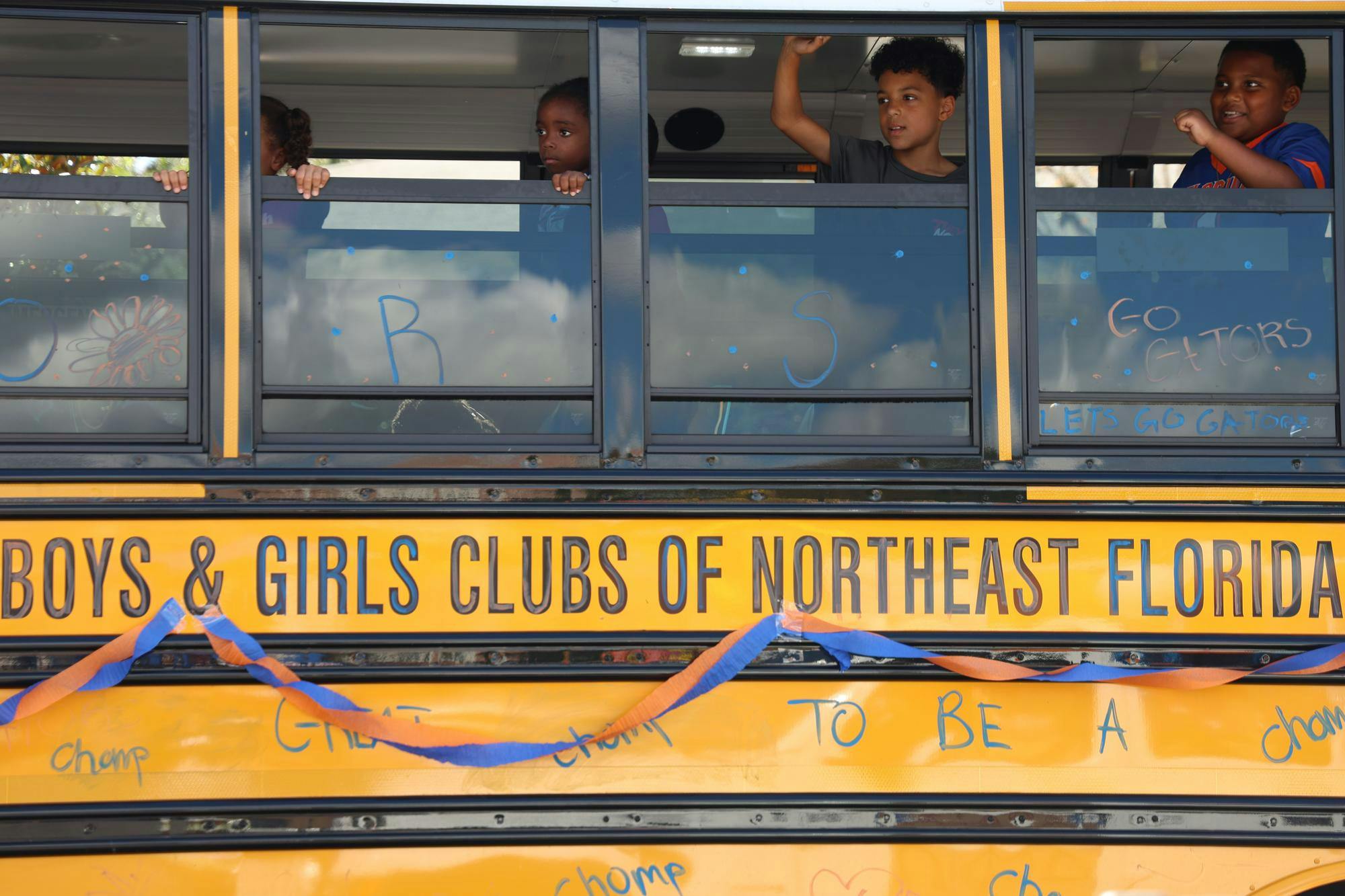 Students from the Boys & Girls Club of Northeast Florida wave out of a bus window during the UF Homecoming Parade on Friday, Oct. 17, 2025.
