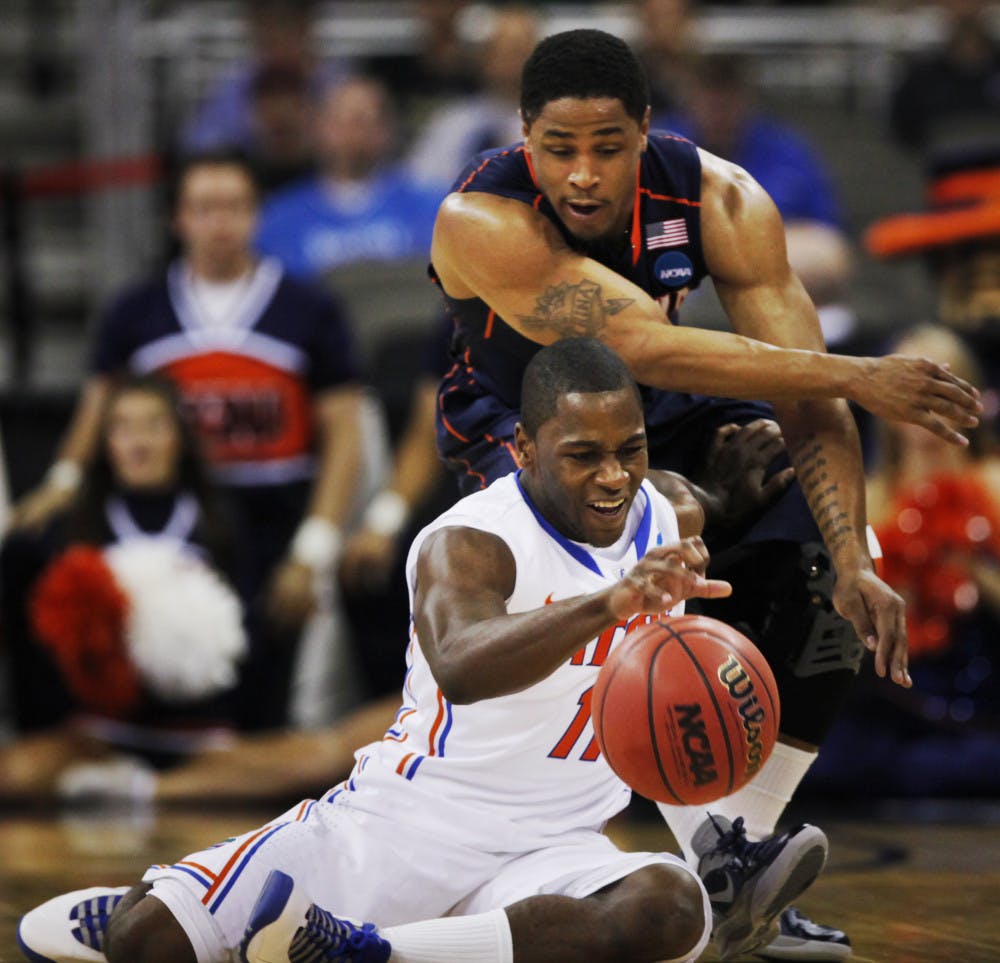 Florida guard Erving Walker (11) controls the ball while covered by Virginia guard Jontel Evans (1) during the first half of a second-round NCAA college basketball tournament game at CenturyLink Center in Omaha, Neb., Friday, March 16, 2012. (AP Photo/Nati Harnik)