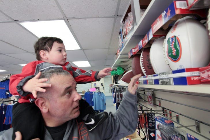 Anthony Biasella holds his son, Jacob, on his shoulders as they look at discounted Gator products in Gator Shop on University Avenue.