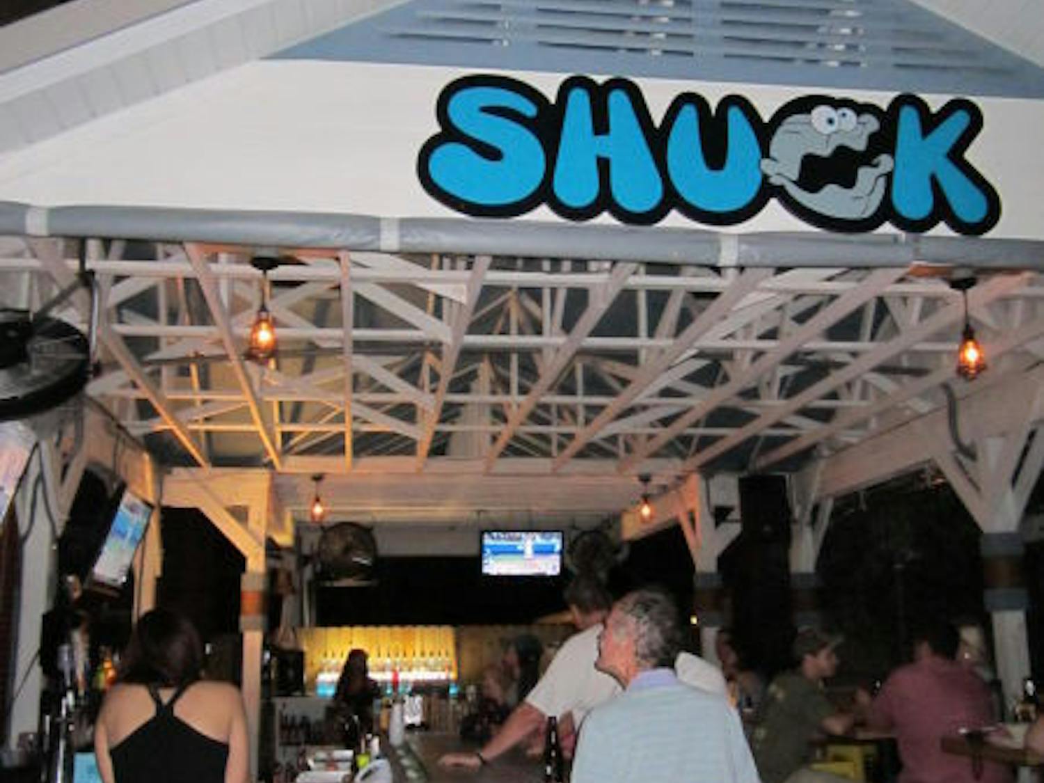 Customers at Shuck Raw Bar and Restaurant in Midtown sit outside watching TV at the bar and chatting among friends. They can enjoy seafood and drinks there and a free shot at sunset.