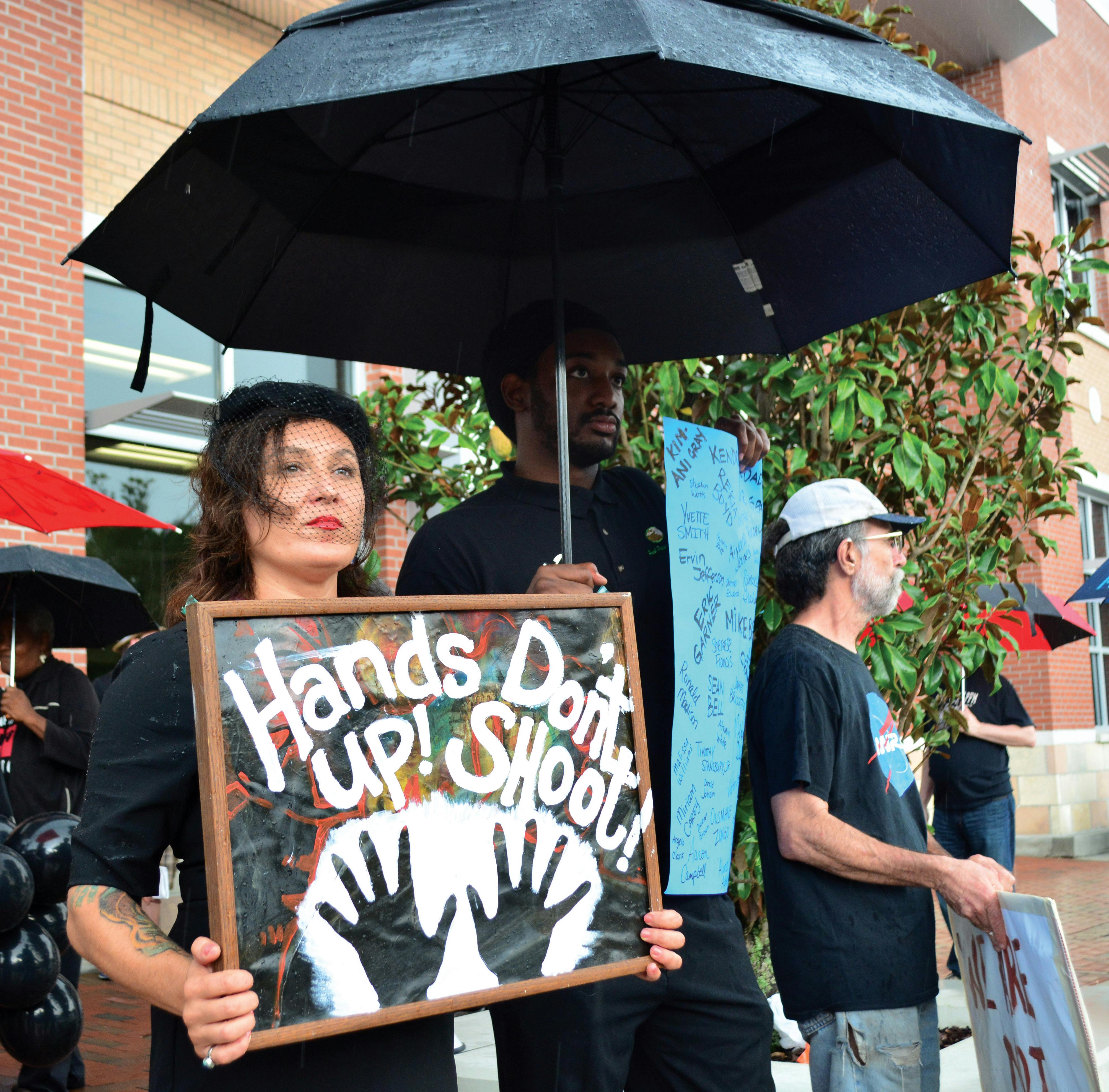 FERGUSON - Tia Ma, a local massage therapistm and Herbert Polite Jr., hold signs during "National Moment of Silence: Gainesville," a vigil and moment of silence held to pay respect to the victims of police shootings and brutality in front of the Gainesville Police Department on August 14.