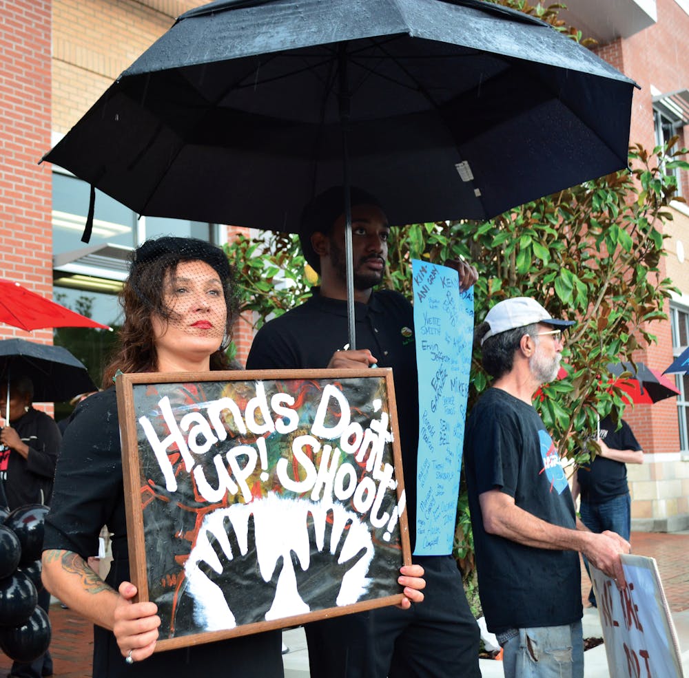 <p>FERGUSON - Tia Ma, a local massage therapistm and Herbert Polite Jr., hold signs during "National Moment of Silence: Gainesville," a vigil and moment of silence held to pay respect to the victims of police shootings and brutality in front of the Gainesville Police Department on August 14.</p>