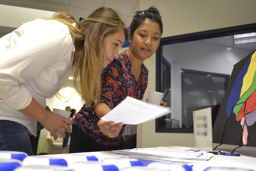 Mirsada Serdarevic (left), 24, and Shivani R. Khan, 28, both UF epidemiology PhD students, peruse an information table at UF HealthStreet during the Our Community, Our Health event Sept. 24, 2015. Khan picked up a flier for a 6-week dance program held by the UF Center for Arts in Medicine, which both girls said they will attend.