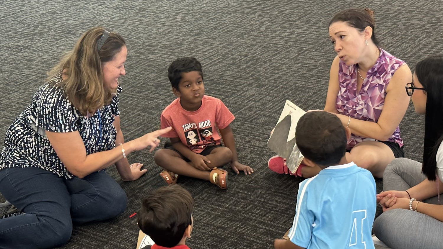 Volunteers with the Latina Women’s League (left, upper right) sit down to read “¿De quién eres, ratóncito?” at the Tower Road Public Library on Saturday, Oct. 21, 2023. Voluntarios de la Liga de Mujeres Latinas (izquierda, arriba a la derecha) se sientan a leer “¿De quién eres, ratóncito?” en la biblioteca pública de Tower Road el 21 de octubre de 2023.