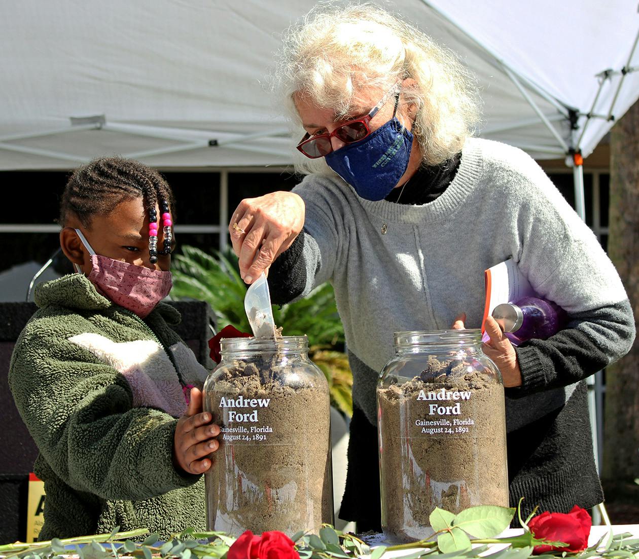 Alachua County Commissioner Marihelen Wheeler, 69, (right) and her granddaughter Tashayla Downer, 8, (left) fill a jar with soil to honor Andrew Ford at the Gainesville Soil Collection Ceremony on Feb. 20, 2021. Ford was lynched in Gainesville on Aug. 24, 1891, according to a pamphlet from the Alachua County Community Remembrance Project.