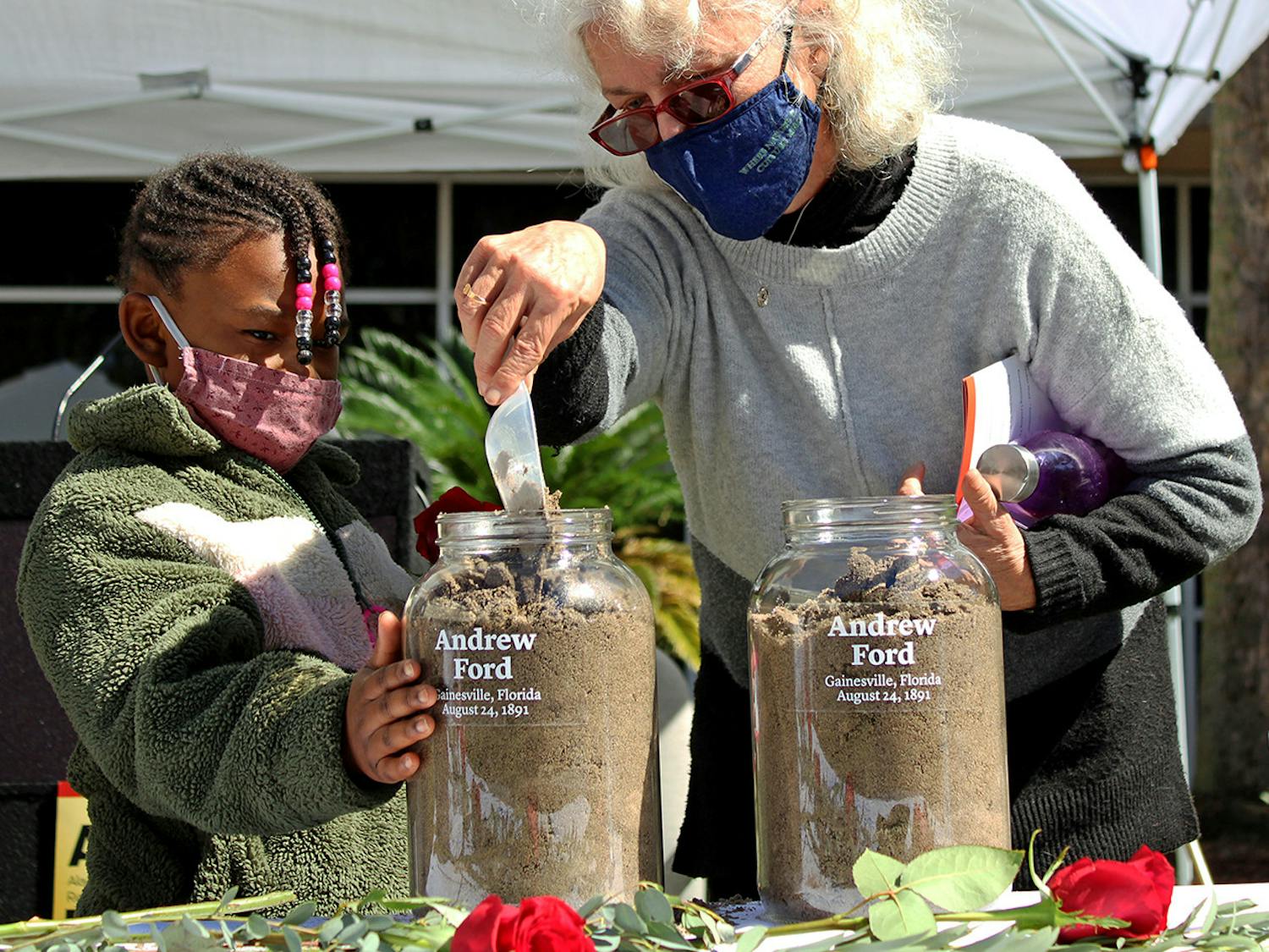 Alachua County Commissioner Marihelen Wheeler, 69, (right) and her granddaughter Tashayla Downer, 8, (left) fill a jar with soil to honor Andrew Ford at the Gainesville Soil Collection Ceremony on Feb. 20, 2021. Ford was lynched in Gainesville on Aug. 24, 1891, according to a pamphlet from the Alachua County Community Remembrance Project.