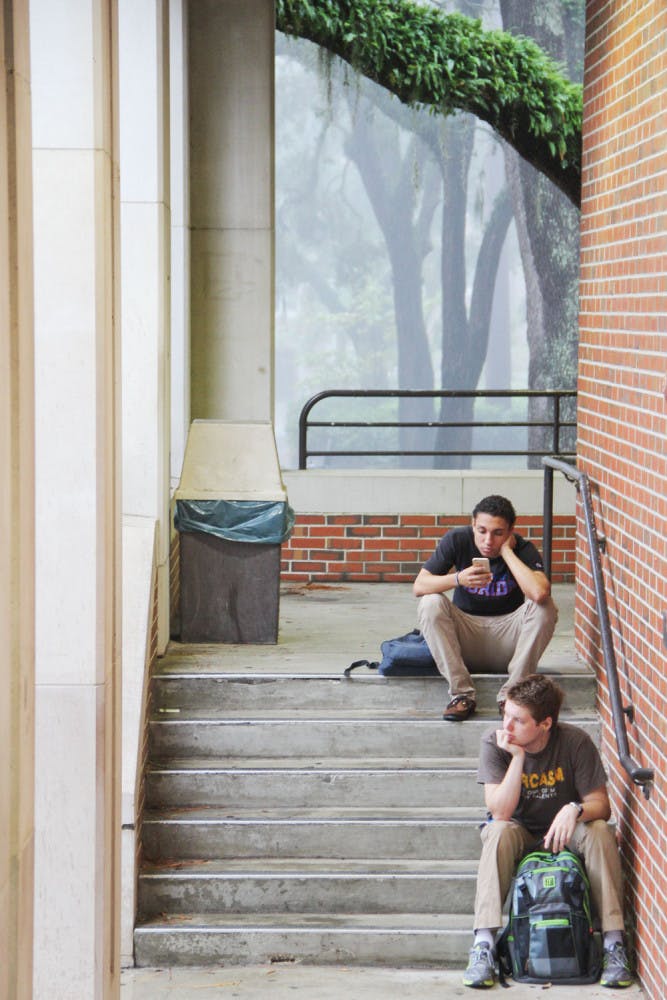 UF finance sophomore Mauricio Vazquez (top) and mechanical engineering freshman Gregory Aumann take shelter near the Chemistry Lab during a storm.
