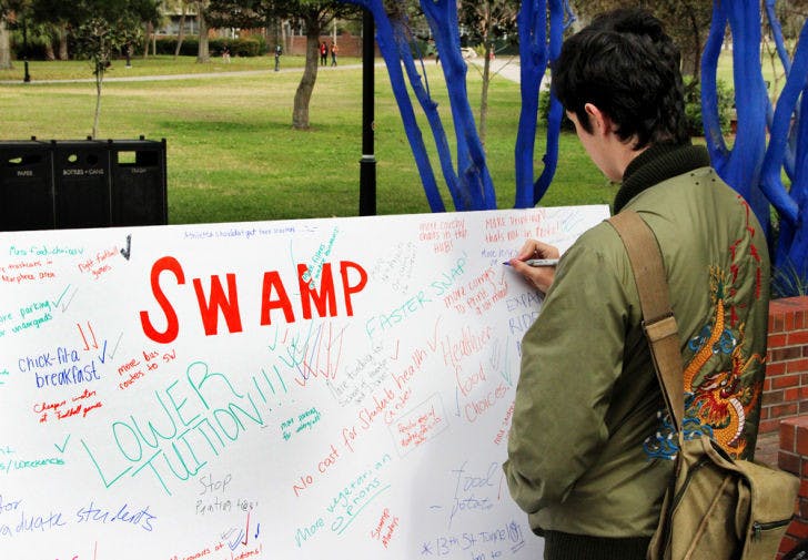 Gavin O’Leary, a 20-year-old UF nuclear engineering student, writes, “Campus needs more buses,” on a Swamp Party board.