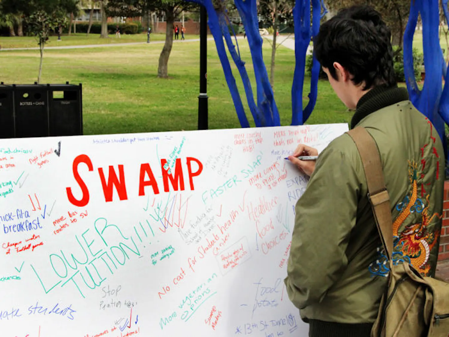 Gavin O’Leary, a 20-year-old UF nuclear engineering student, writes, “Campus needs more buses,” on a Swamp Party board.