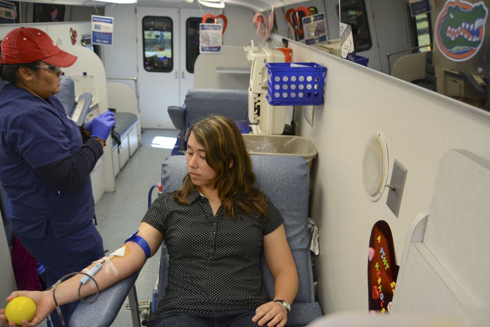 <p>Mandy Moss, a 20-year-old UF mechanical and aerospace engineering junior, squeezes a stress ball as she donates blood in one of the LifeSouth buses on the Reitz Union North Lawn on Monday afternoon. UF is competing against the University of Kentucky to see who can collect the most blood as part of LifeSouth’s “What Colors Do You Bleed?” blood drive.</p>