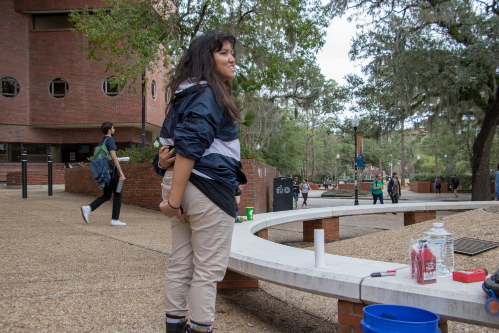 Sophia Ahmed, a UF materials science and engineering sophomore, stands near the rock sculpture on Turlington Plaza applying washable red dye on her pants. Ahmed, 20, is an organizer for “Are You Seeing Red?,” and said the point is to raise awareness about the lack of free menstrual products on campus.