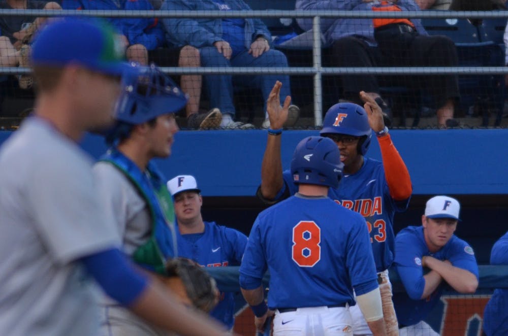 <p>UF outfielder Buddy Reed (23) celebrates with teammate Deacon Liput while an FGCU player walks back onto the field during Florida's 8-4 win against Florida Gulf Coast on Feb. 20, 2016, at McKethan Stadium.</p>