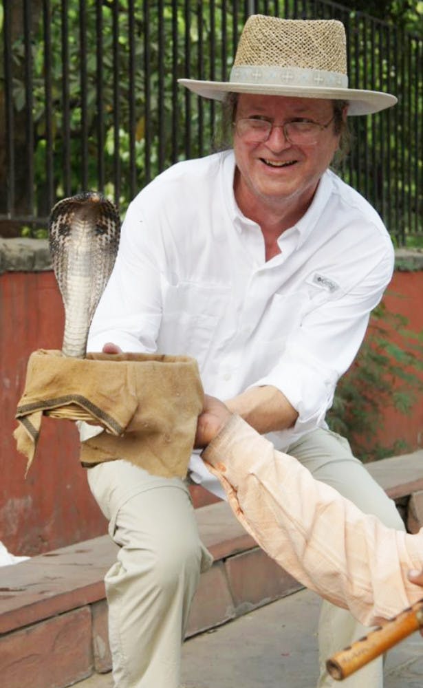 Gar Hoflund plays with a cobra outside of the Memorial to Gandhi in Delhi, India.