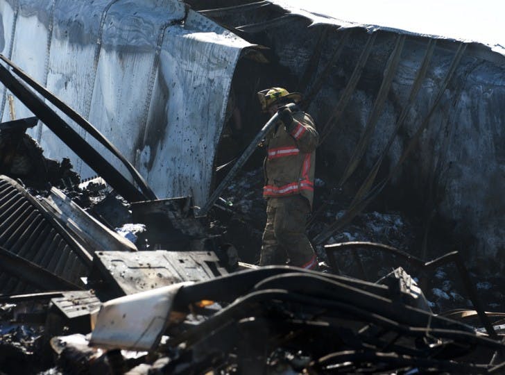 An Alachua County Fire Rescue Worker carries a hose through the wreckage of a semitrailer involved the southbound accident on Interstate 75 Sunday afternoon.&nbsp; The north and southbound accident claimed a total of 10 lives.