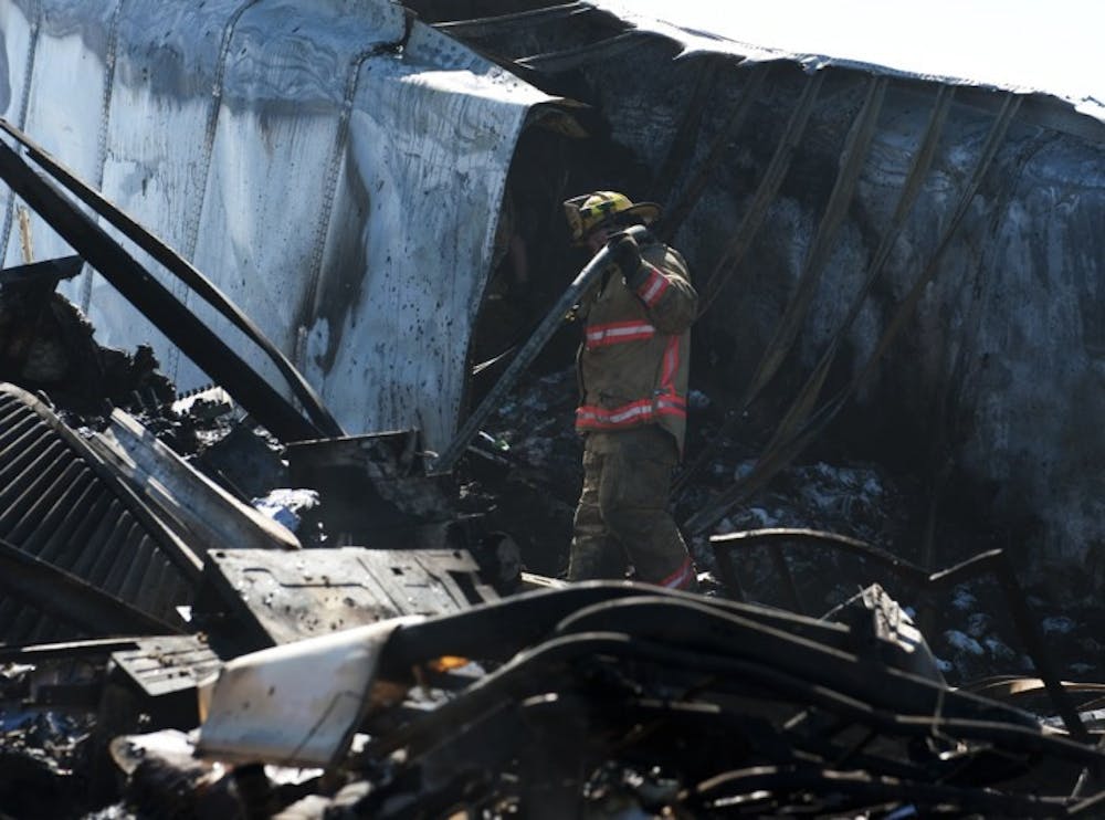 <p>An Alachua County Fire Rescue Worker carries a hose through the wreckage of a semitrailer involved the southbound accident on Interstate 75 Sunday afternoon.&nbsp; The north and southbound accident claimed a total of 10 lives.</p>