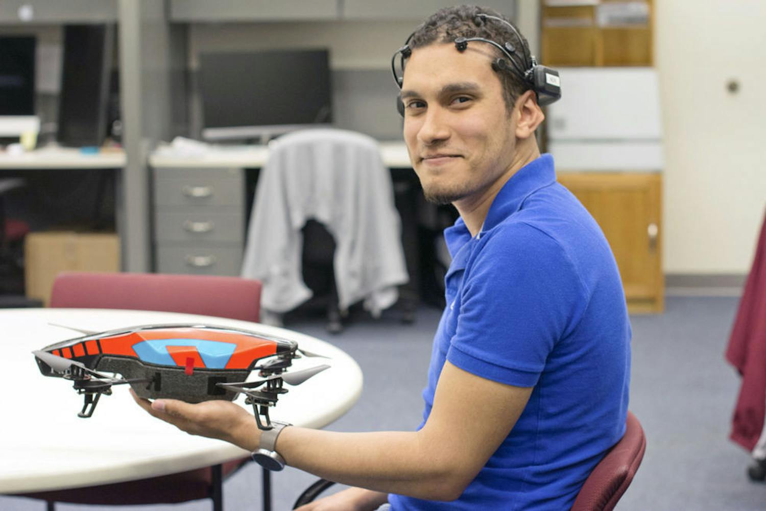 Marvin Andujar, a 25-year-old UF human-centered computing doctoral student, poses for a photo with a mind-controlled drone that he and his partner, Chris Crawford, programmed.