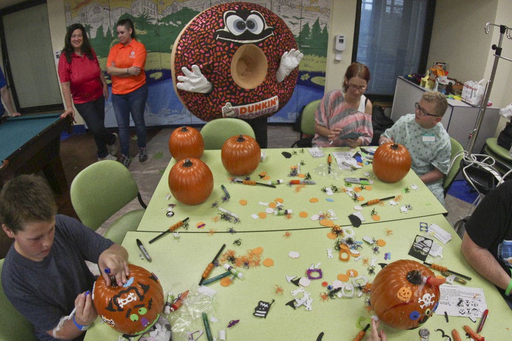 Children and parents gather around an arts and crafts table to decorate pumpkins with Sprinkles, the Dunkin' Donuts’ mascot, on Oct. 27, 2015. Dunkin’ Donuts donated 40 pumpkins for kids to participate in a no-carve pumpkin activity.
