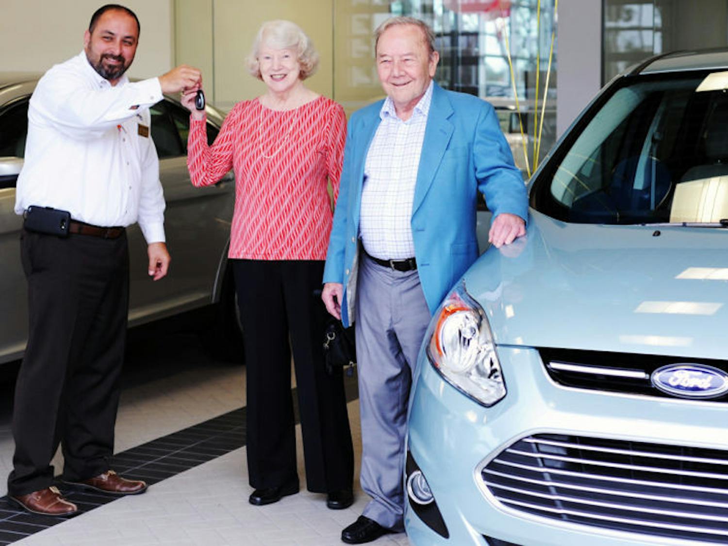 Michael Grimaldi, General Sales Manager of Parks Ford Lincoln of Gainesville, hands the keys to a 2014 Ford C-MAX Hybrid to Albert Traversa and his wife Mary Hausler.
