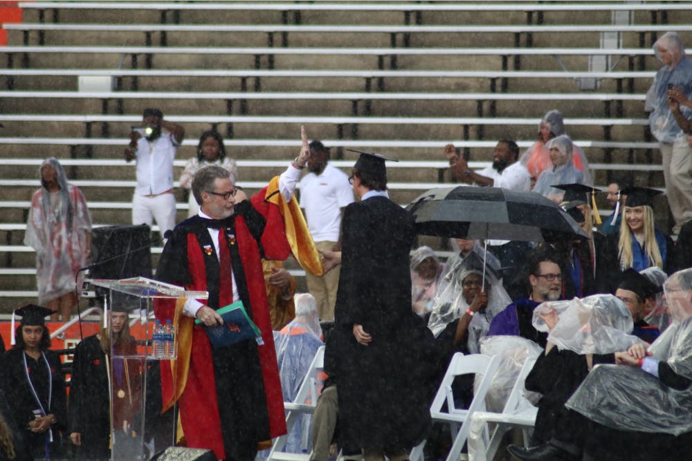 College of Liberal Arts and Sciences Dean, David Richardson, gestures to pause the commencement ceremony. Richardson announced the ceremony would be delayed by 30 minutes, but the ceremony was later moved to an insidehallway of the stadium.