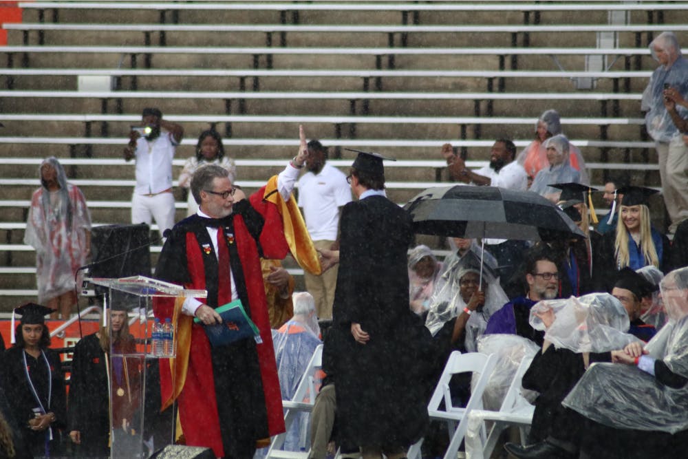<div>College of Liberal Arts and Sciences Dean, David Richardson, gestures to pause the commencement ceremony. Richardson announced the ceremony would be delayed by 30 minutes, but the ceremony was later moved to an inside</div><div>hallway of the stadium.</div>