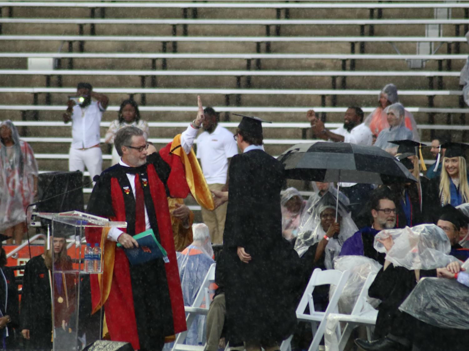 College of Liberal Arts and Sciences Dean, David Richardson, gestures to pause the commencement ceremony. Richardson announced the ceremony would be delayed by 30 minutes, but the ceremony was later moved to an insidehallway of the stadium.