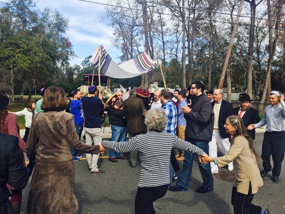 <p dir="ltr"><span>Members of the Lubavitch Chabad Jewish Center dance in celebration. The center welcomed its fifth Torah Sunday.</span></p><p><span> </span></p>