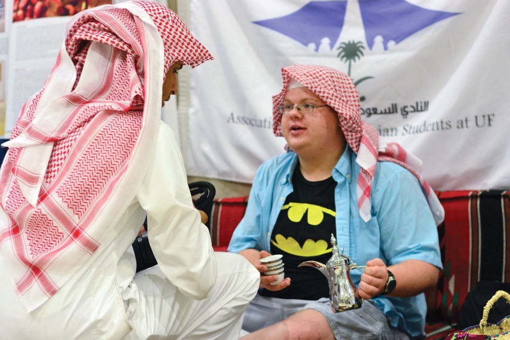 Mohammed Alqarni, 26, shows UF chemical engineering freshman Alex Logsdon, 18, how to hold a tea set during the Saudi Arabian National Day event in the Reitz Union on Tuesday afternoon.