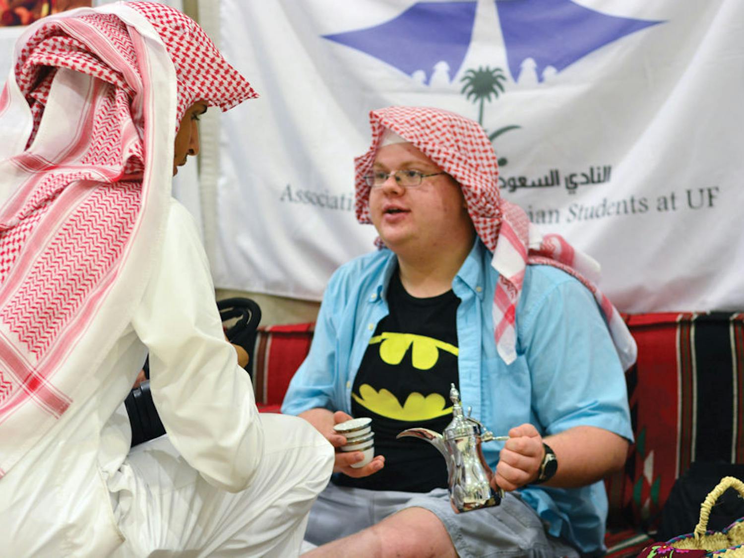 Mohammed Alqarni, 26, shows UF chemical engineering freshman Alex Logsdon, 18, how to hold a tea set during the Saudi Arabian National Day event in the Reitz Union on Tuesday afternoon.