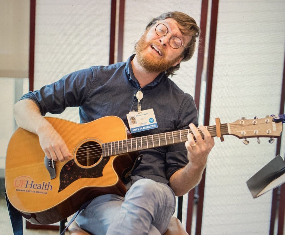 <p><span>Live on the Arts in Medicine Facebook all-request concert, Musician in Residence Michael Claytor sings and strums his guitar.</span></p>