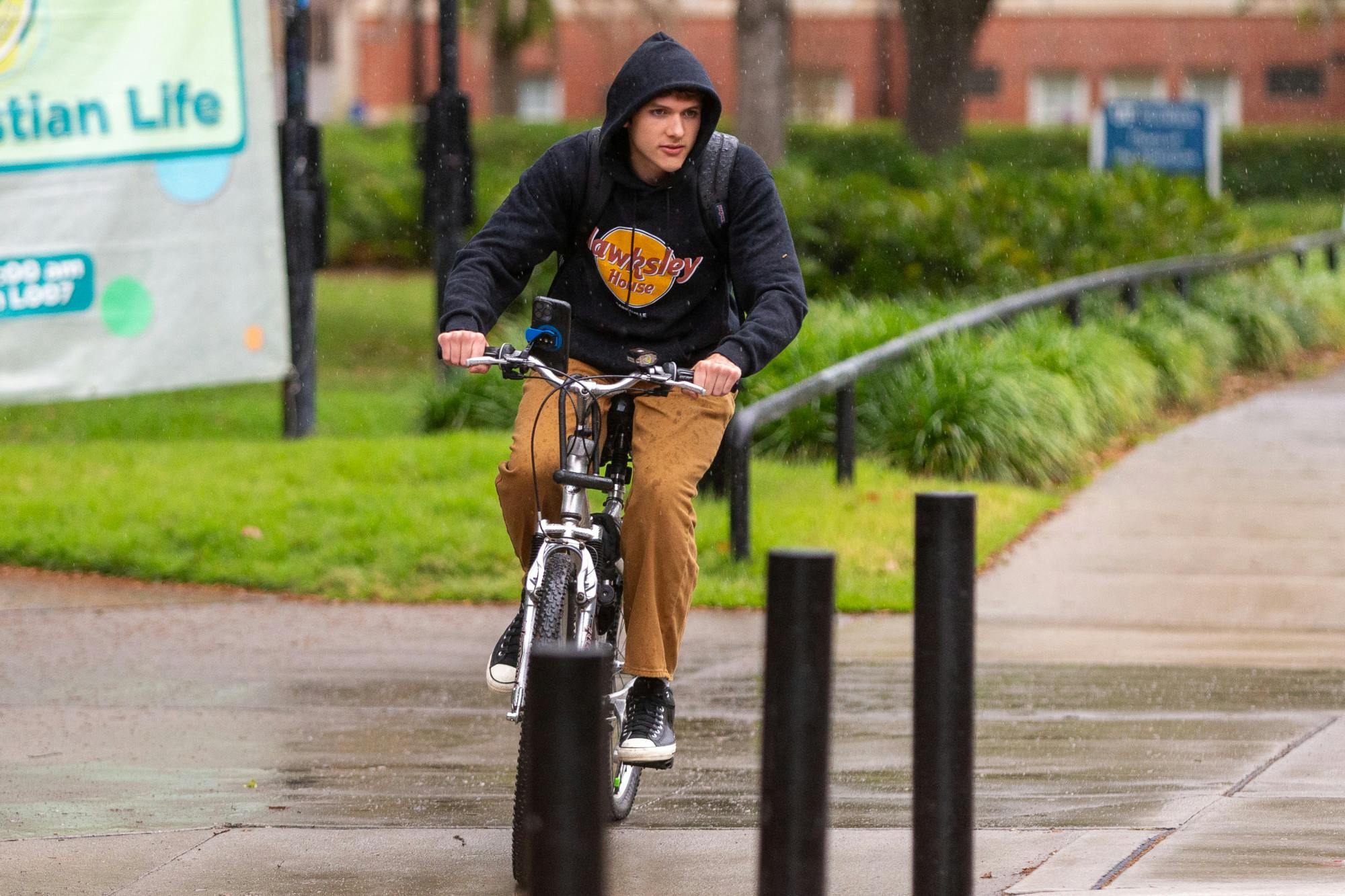 A student is seen biking through the Plaza of the Americas during the rainy morning of Wednesday, March 27, 2024.