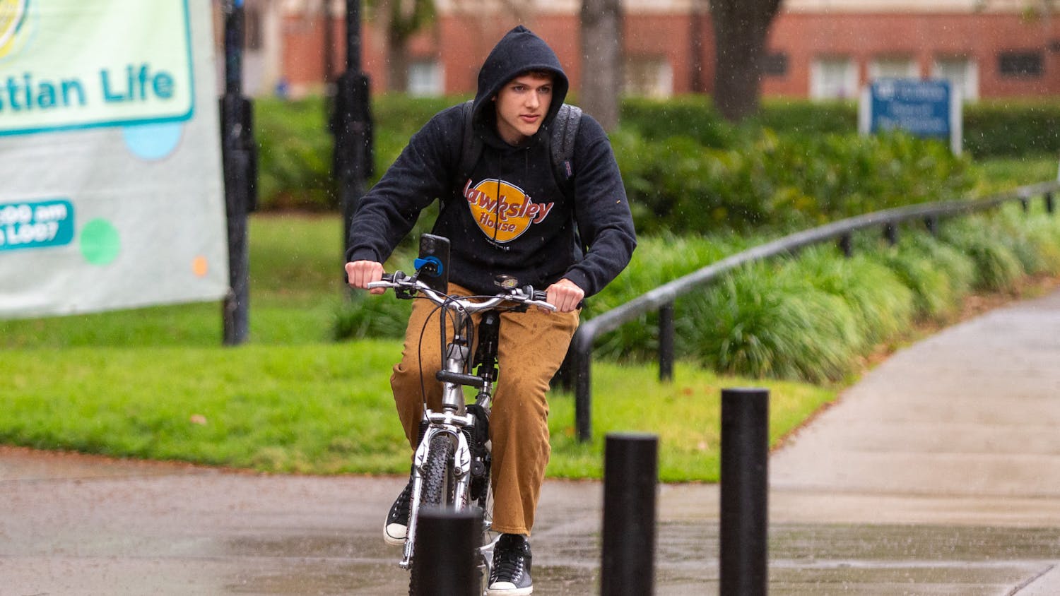 A student is seen biking through the Plaza of the Americas during the rainy morning of Wednesday, March 27, 2024.