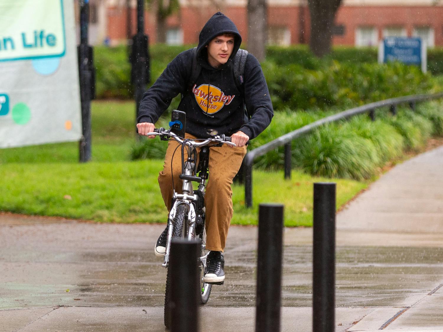 A student is seen biking through the Plaza of the Americas during the rainy morning of Wednesday, March 27, 2024.