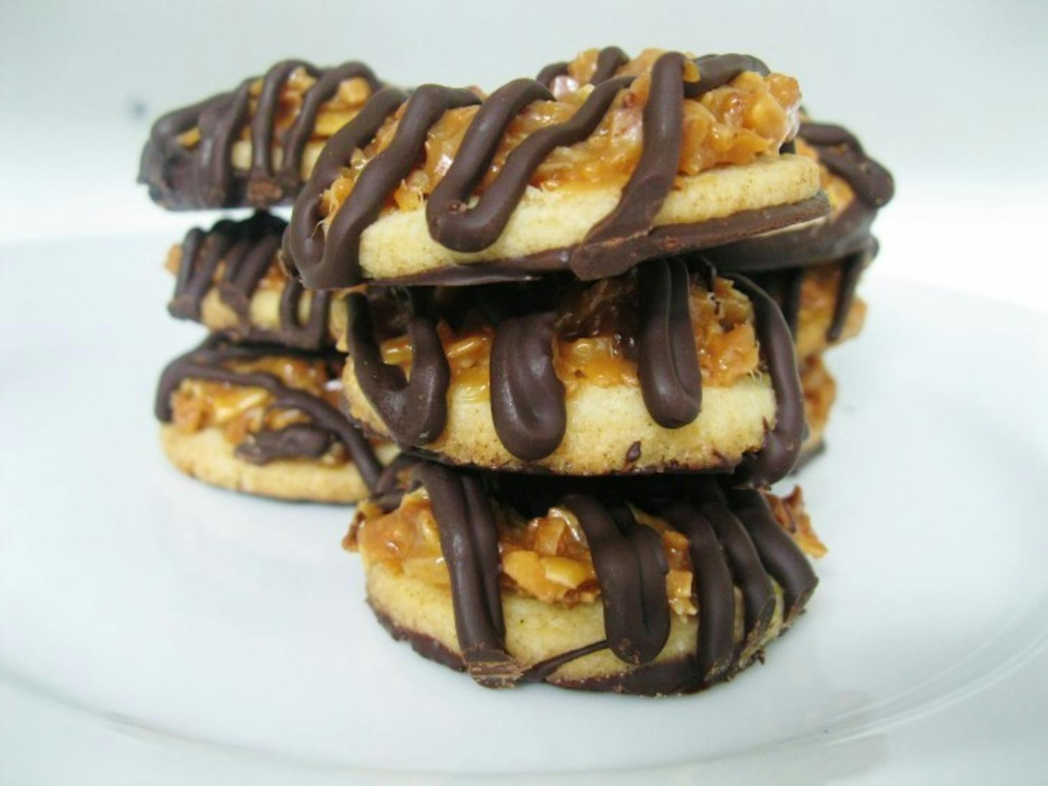 Samoas are simple shortbread cookies with a hole in the center, covered in a caramel and toasted coconut topping and then dipped in and streaked with rich dark chocolate.