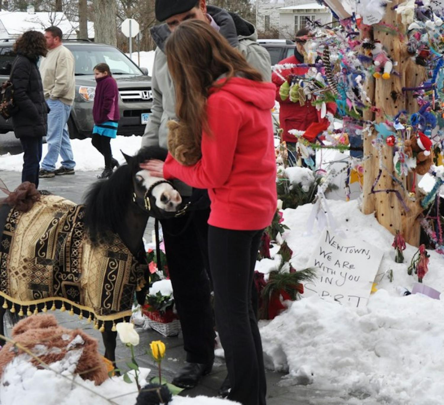 Magic, a Gentle Carousel mini horse of High Springs, comforts a Newtown, Conn., girl at a memorial site in the town. Gentle Carousel Miniature Therapy Horses is visiting the Newtown community to aid in the healing process.