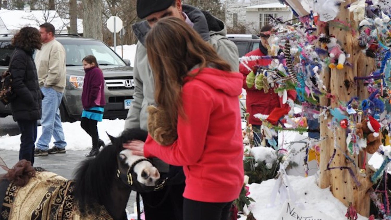 Magic, a Gentle Carousel mini horse of High Springs, comforts a Newtown, Conn., girl at a memorial site in the town. Gentle Carousel Miniature Therapy Horses is visiting the Newtown community to aid in the healing process.