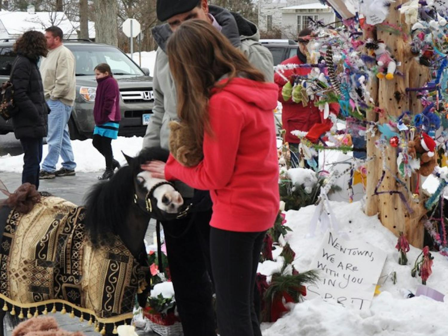 Magic, a Gentle Carousel mini horse of High Springs, comforts a Newtown, Conn., girl at a memorial site in the town. Gentle Carousel Miniature Therapy Horses is visiting the Newtown community to aid in the healing process.