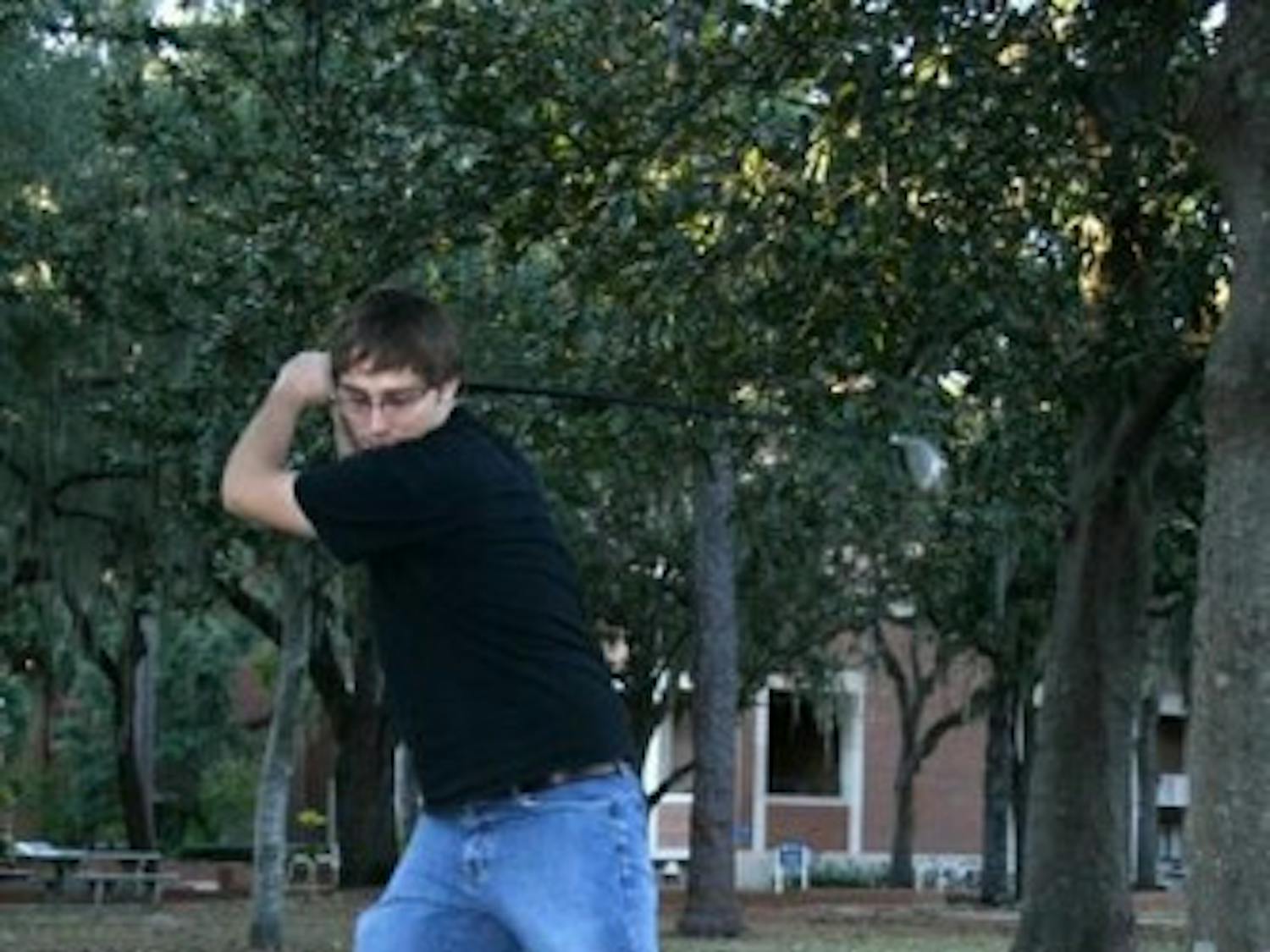 FORE! Jeremiah Tattersall, a UF senior, plays urban golf on the Plaza of the Americas Sunday afternoon. Tattersall said he gathers with friends to play every Wednesday. Urban golf is a sport where people choose their own tee-off area and hole in an urban or unconventional location. (Charlie Doerner / Alligator)