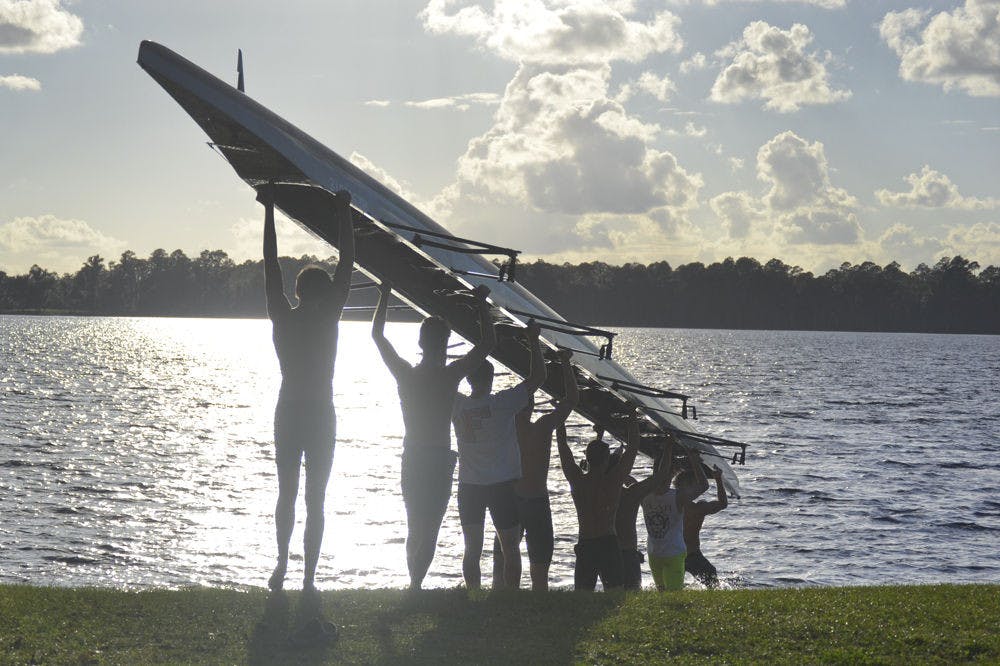 <p>The UF Men’s Crew club carry their boat into the waters of Lake Alto in Waldo on Oct. 28, 2015. Since their boathouse on Newnan’s Lake has been condemned, the club has to drive 45 minutes to practice every day.</p>
