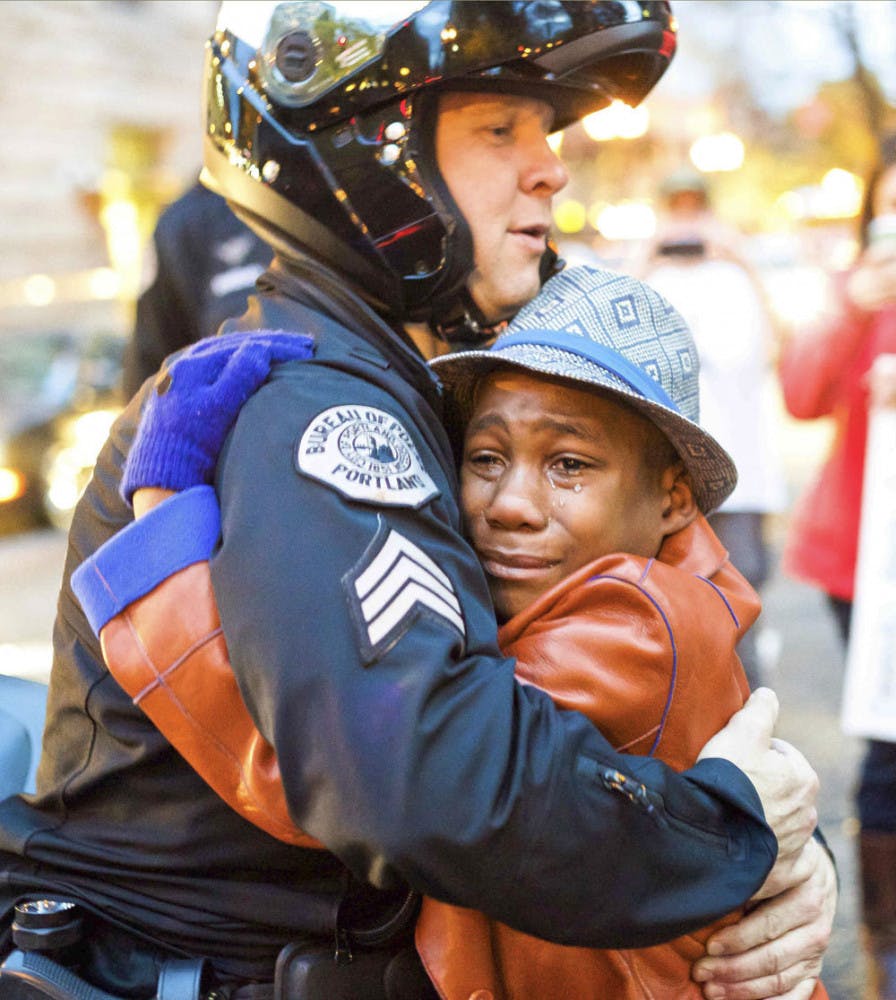 In this Tuesday, Nov. 25, 2014 photo provided by Johnny Nguyen, Portland police Sgt. Bret Barnum, left, and Devonte Hart, 12, hug at a rally in Portland, Ore., where people had gathered in support of the protests in Ferguson, Mo. (AP Photo/Johnny Huu Nguyen)