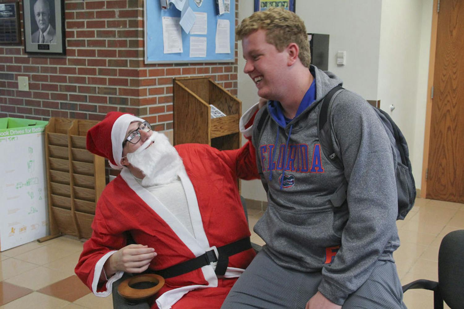 Nicolas Lomurro, a 19-year-old UF finance freshman, sits on the lap of Marty Cohen, an 18-year-old UF biology freshman, in Hume Hall on Dec. 8, 2015. Cohen played Santa at the “Snowflakes and Santa” event to relieve students’ stress before finals.